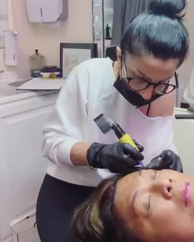 Tereza in her studio, in gloves, performing a permanent makeup brow treatment on a client